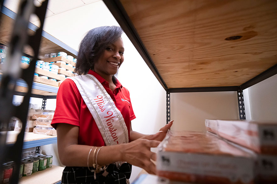 Student stocks shelves at the food pantry