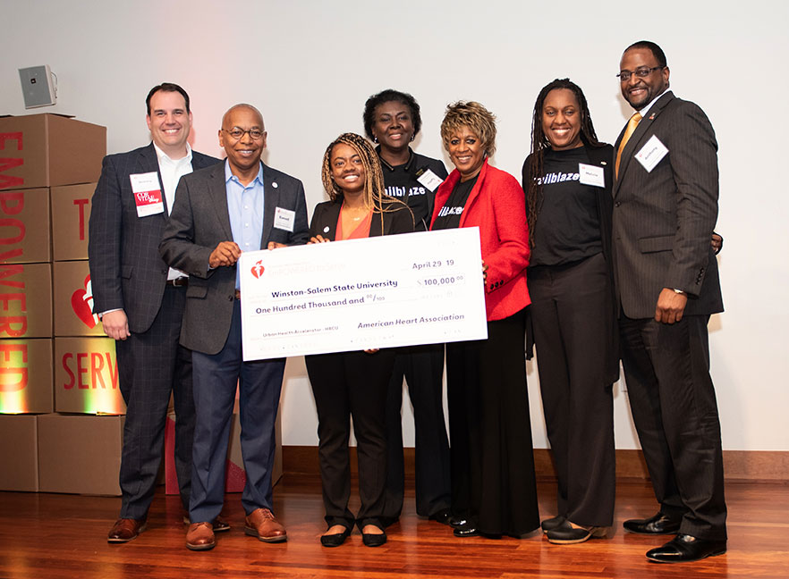 Group stands with large check for presentation of $100,000 grant