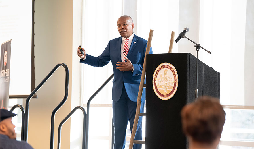 Chancellor Robinson stands at the podium on stage at the summit