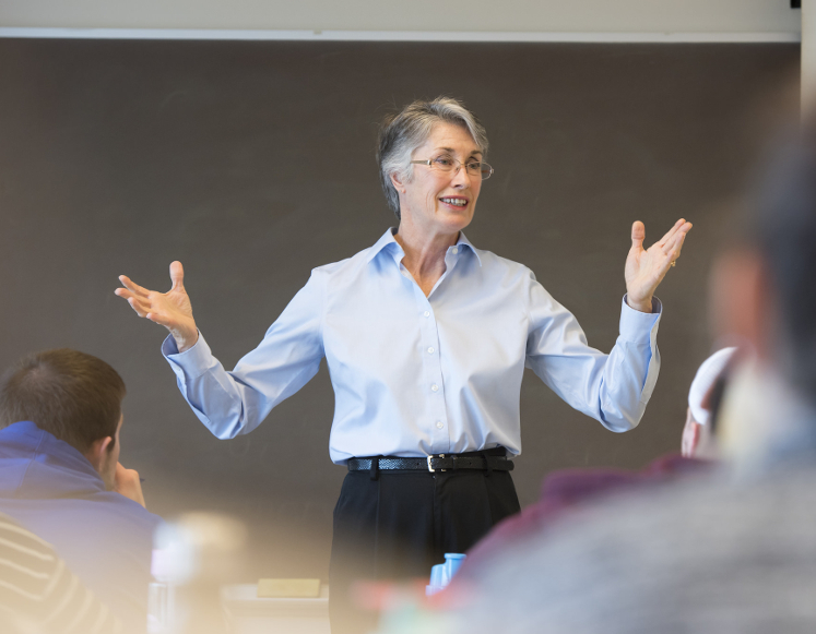 a woman speaking to a room of people.